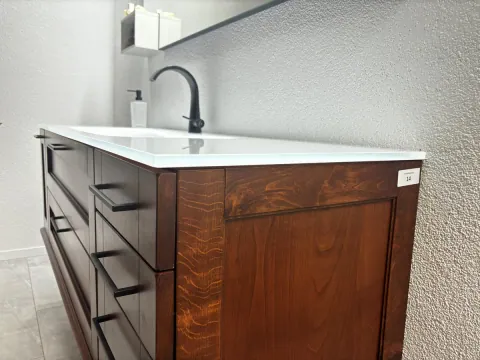 Seitliche Gesamtansicht von Koje 14 mit Glaswaschtisch, Holzfronten und schwarzen Griffen